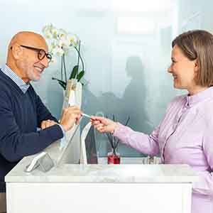 Man in blue sweater paying for services at marble countertop