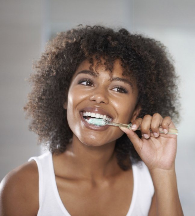 Woman brushing teeth to prevent dental emergencies