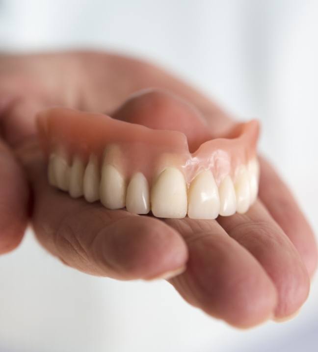 Hand holding a full denture