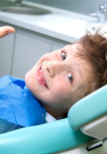 young child smiling while in dental chair 