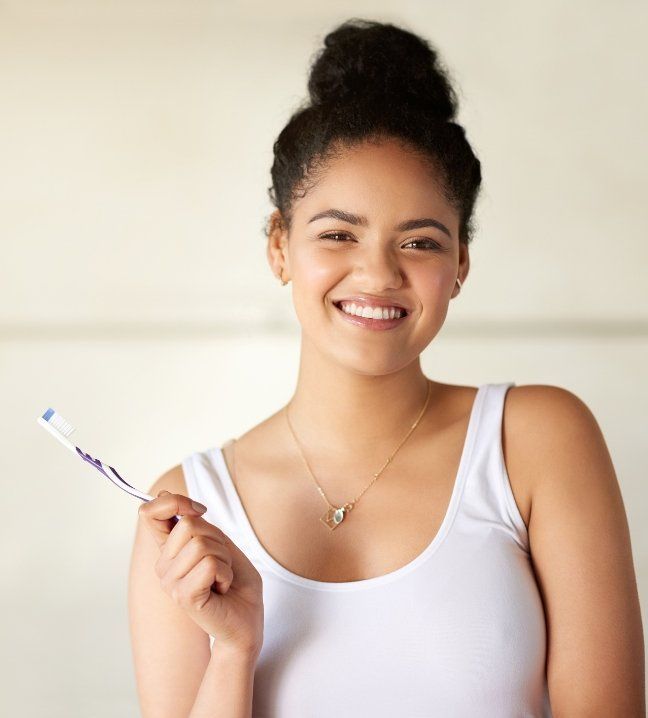 Woman brushing teeth to take care of her smile after wisdom tooth extraction