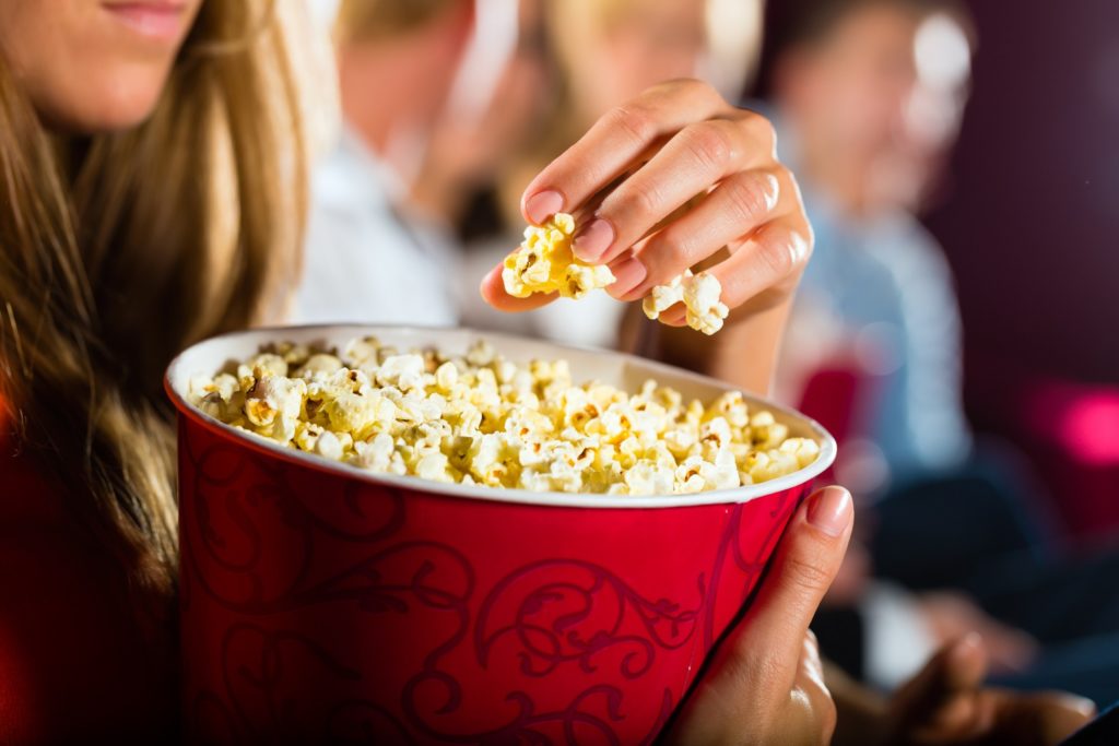 Closeup of woman grabbing handful of popcorn at movie theater