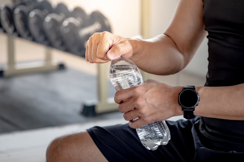 A guy at a gym opening a bottle of water